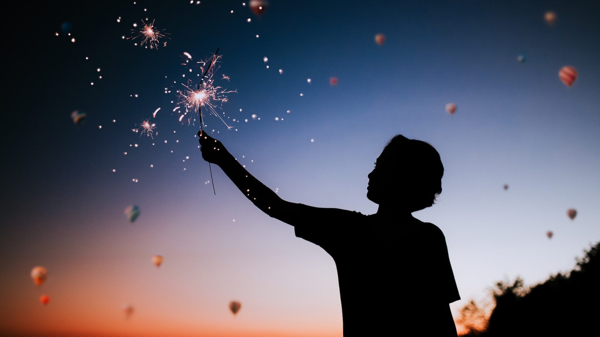 boy holding sparkler firework at night