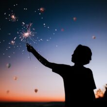 boy holding sparkler firework at night